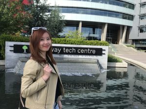 Asian woman with brown hair standing in front of water fountain. The sign behind her reads "broadway tech centre", but the "broad" is covered.